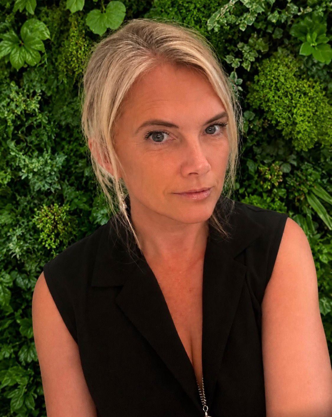 Bex Hamilton, biophilic design specialist, photographed against a living plant wall